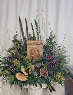 a white vase filled with lots of different types of flowers and plants on top of a table