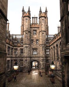 an old building with many windows and some people walking around the walkways in front of it