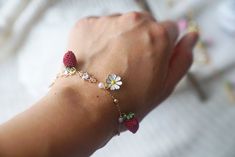 a person wearing a bracelet with flowers and beads on their wrist, holding onto the arm