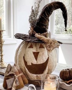 a decorated pumpkin sitting on top of a table next to candles and other decor items