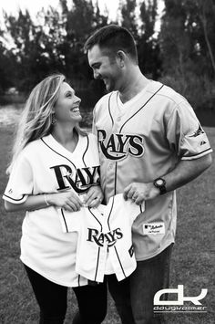 black and white photograph of two baseball players smiling at each other while standing in the grass