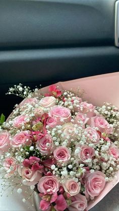 a bouquet of pink roses and baby's breath in the back seat of a car