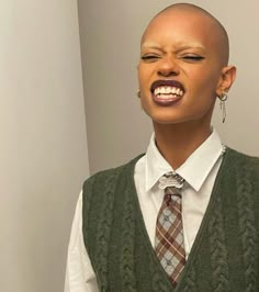 a bald headed man wearing a vest and tie with his mouth open in front of the camera