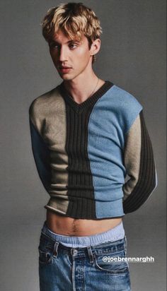 a young man in jeans and a sweater posing for a magazine cover photo with his hands on his hips