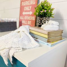 a stack of books sitting on top of a white dresser