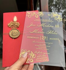 a person holding up a red and gold wedding card