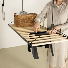 a woman holding a pair of scissors over a bed frame with clothes hanging on it