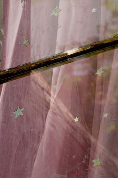 a cat sitting on the window sill in front of a curtain with stars all over it