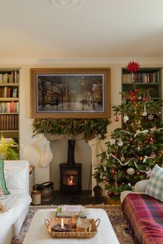 a living room filled with furniture and a christmas tree in front of a fire place