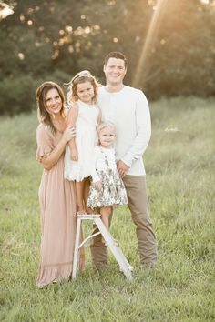 a family posing for a photo in an open field with the sun shining down on them