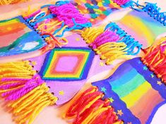 several colorful pieces of cloth with fringes and beads on top of each other, all in different colors