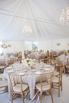 the inside of a white tent with tables and chairs