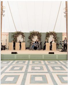 an outdoor stage set up with musical instruments and flowers on the wall in front of it