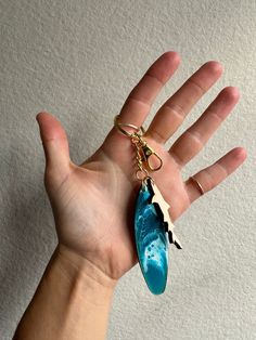 a hand holding a keychain with a blue surfboard on it's side