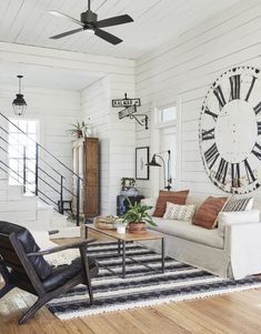 a living room filled with furniture and a large clock mounted to the wall above it