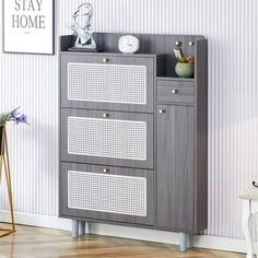 a gray cabinet with three drawers and some pictures on the wall