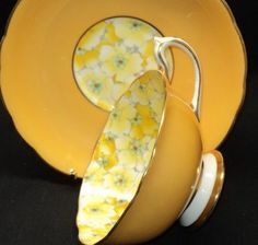 a yellow plate with a banana on it next to an orange bowl and saucer