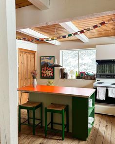 a kitchen with an island and two stools next to it on a hard wood floor