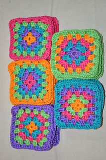 four crocheted squares are arranged on a table