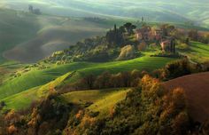 the rolling hills are covered in trees and green grass, with houses on each side