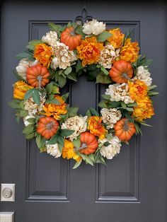 a wreath with pumpkins and flowers on the front door