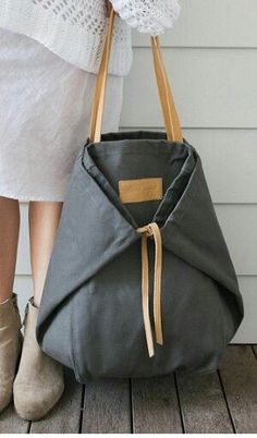 a woman holding a gray purse on top of a wooden floor