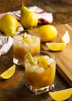 two glasses filled with lemonade sitting on top of a wooden cutting board next to sliced pears