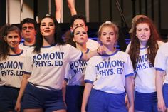 a group of young women standing next to each other in front of a stage backdrop