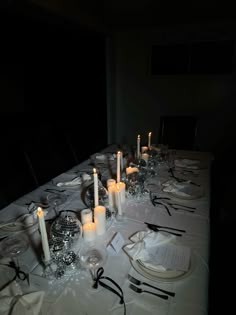 a long table is set with candles and place settings for an elegant dinner or party