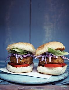 two burgers with lettuce, tomato and onion on a blue platter