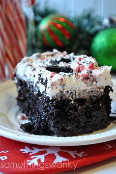 a piece of chocolate cake with white frosting and peppermint on top sitting on a plate