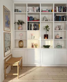 an empty room with white bookcases and wooden flooring on the far wall