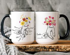 two coffee mugs with flowers on them sitting on a wooden table next to a blanket