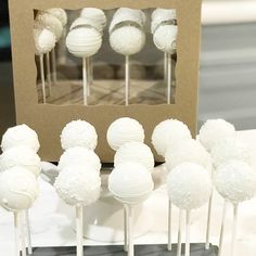 there are many white cake pops on the table and in front of it is a cardboard box