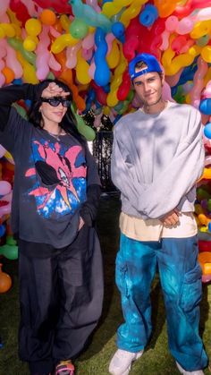 two people standing in front of a bunch of balloons