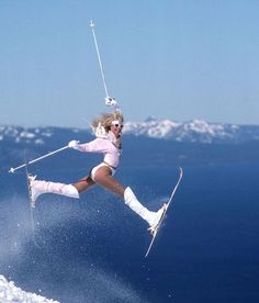 a woman is skiing in the snow with skis on her feet and poles above her head