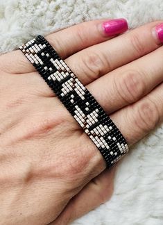 a woman's hand wearing a black and white beaded bracelet