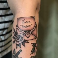 a woman with a tattoo on her arm that says i love mom and has flowers around it