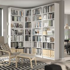 a living room filled with lots of white bookshelves next to a dining table