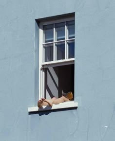 a woman laying on the window sill reading a book