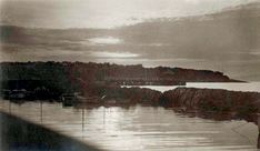 an old black and white photo of some boats in the water near a shore line