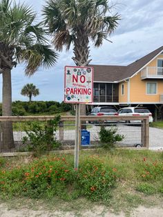 a no parking sign in front of a house with palm trees and flowers around it