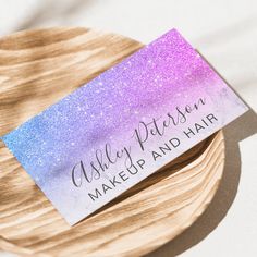 a close up of a business card on a wooden plate with white and purple glitter