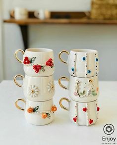 three coffee mugs are stacked on top of each other, decorated with flowers and beads