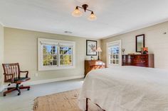 a bedroom with a bed, dresser and two windows in it's center area