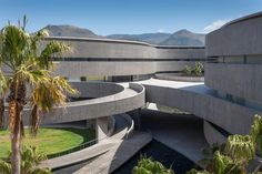 an architecturally designed building with palm trees in the foreground and mountains in the background