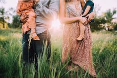 a family standing in tall grass with the sun behind them