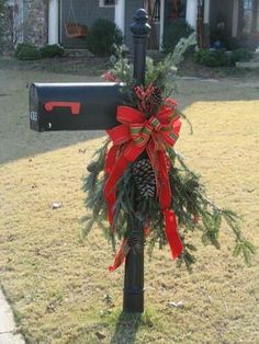 a mailbox decorated with red bows and pine cones is in front of a house