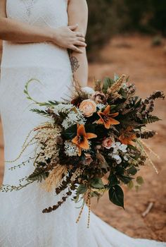 a woman in a wedding dress holding a bridal bouquet with orange and white flowers