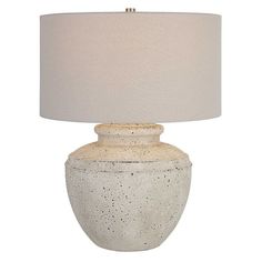 a white table lamp with a beige shade on the base and a light brown drum